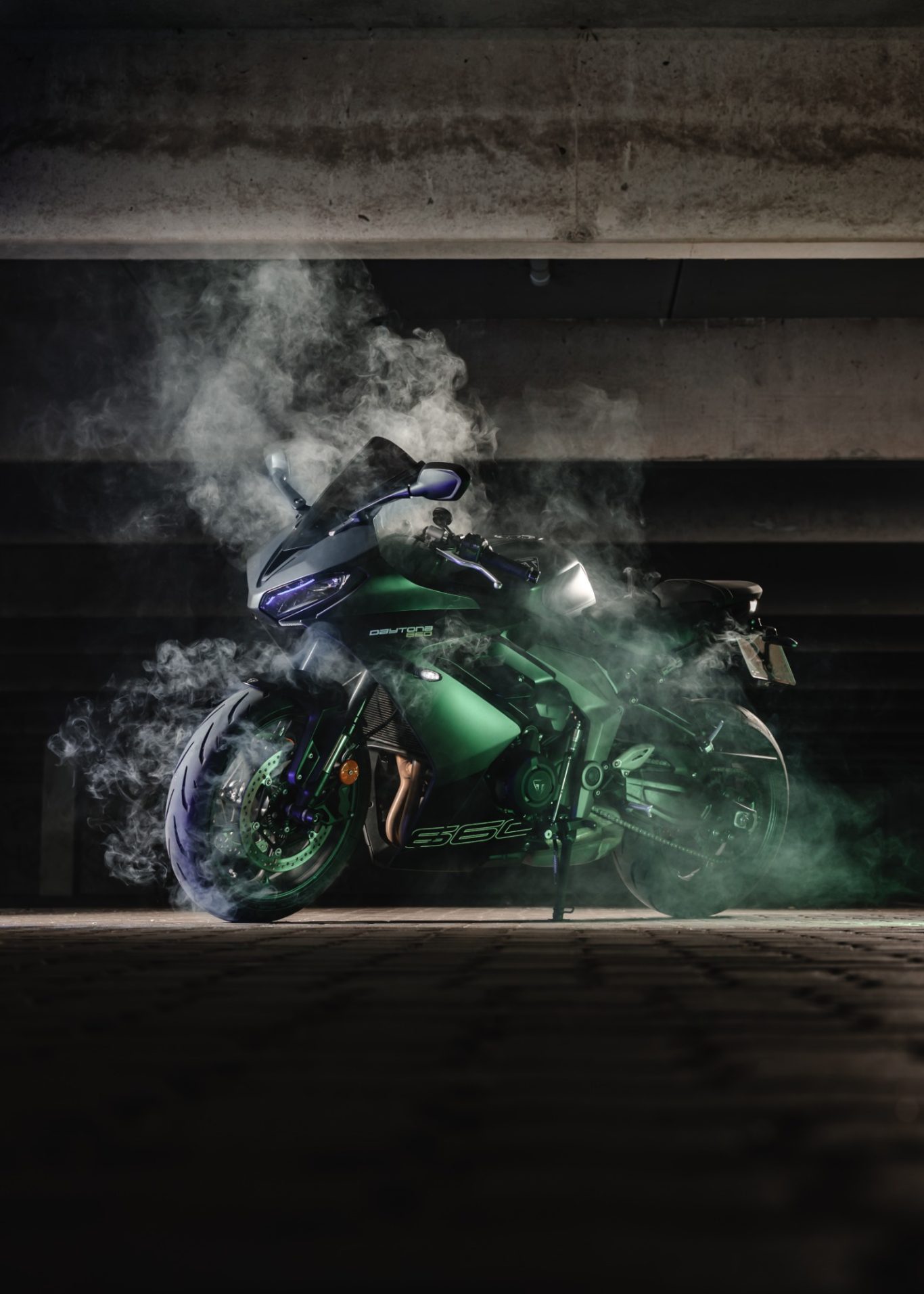 Motorrad in einer dunklen Umgebung mit Rauch und grüner Beleuchtung.