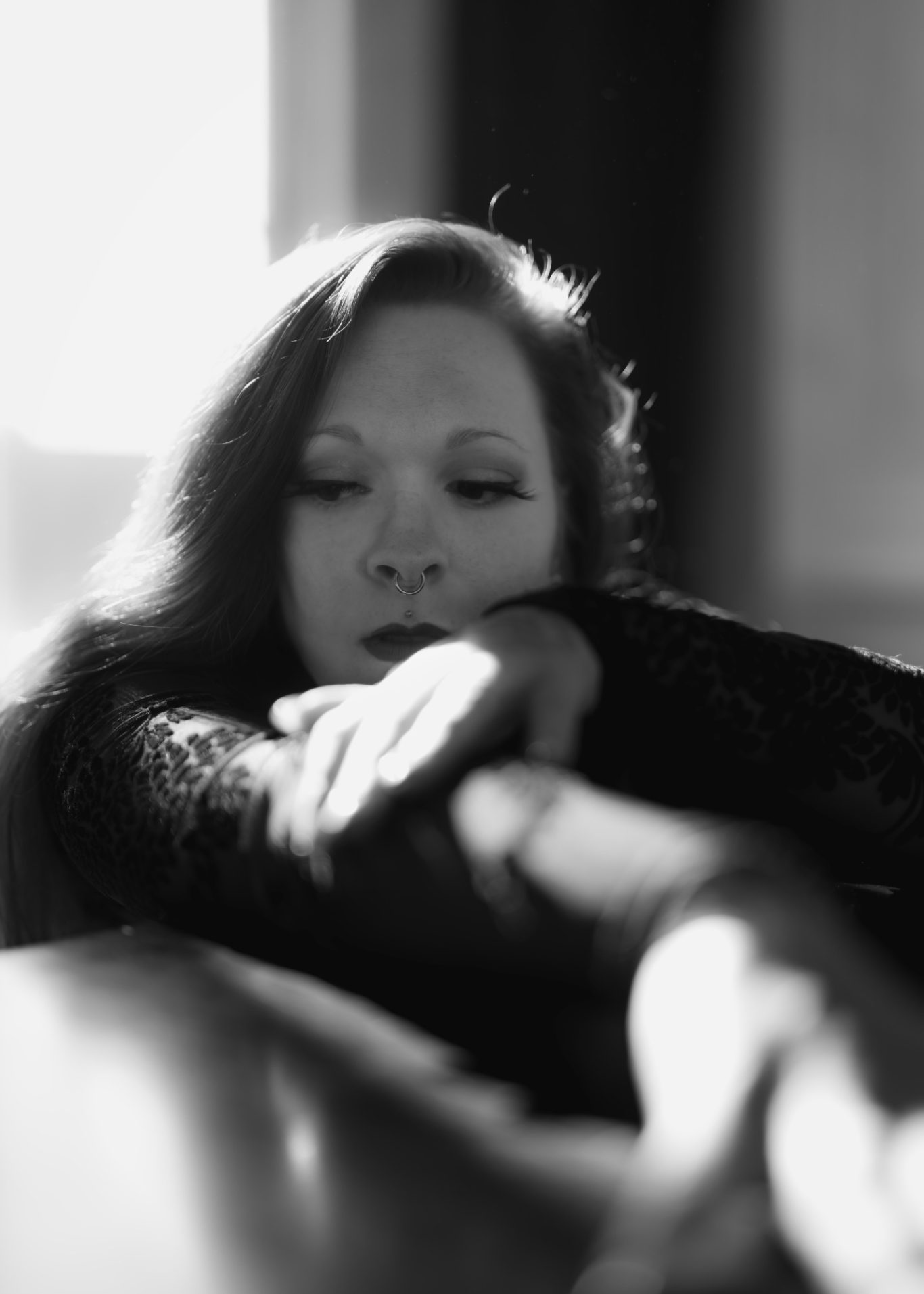 Frau mit langen Haaren, nachdenklicher Blick, Lichtspiel im Hintergrund.