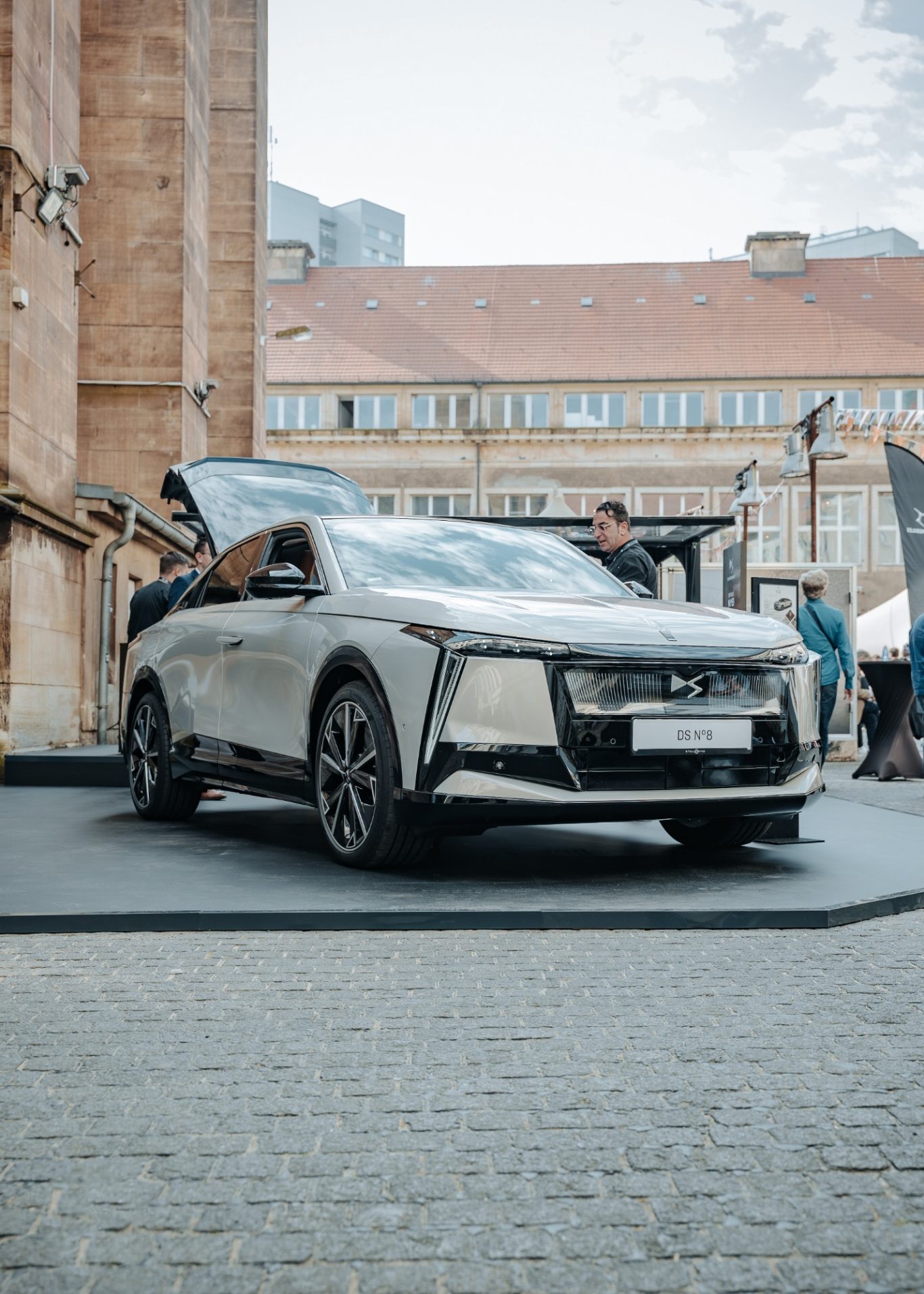 Ein moderner silberner SUV steht auf einem gepflasterten Platz vor historischen Gebäuden.