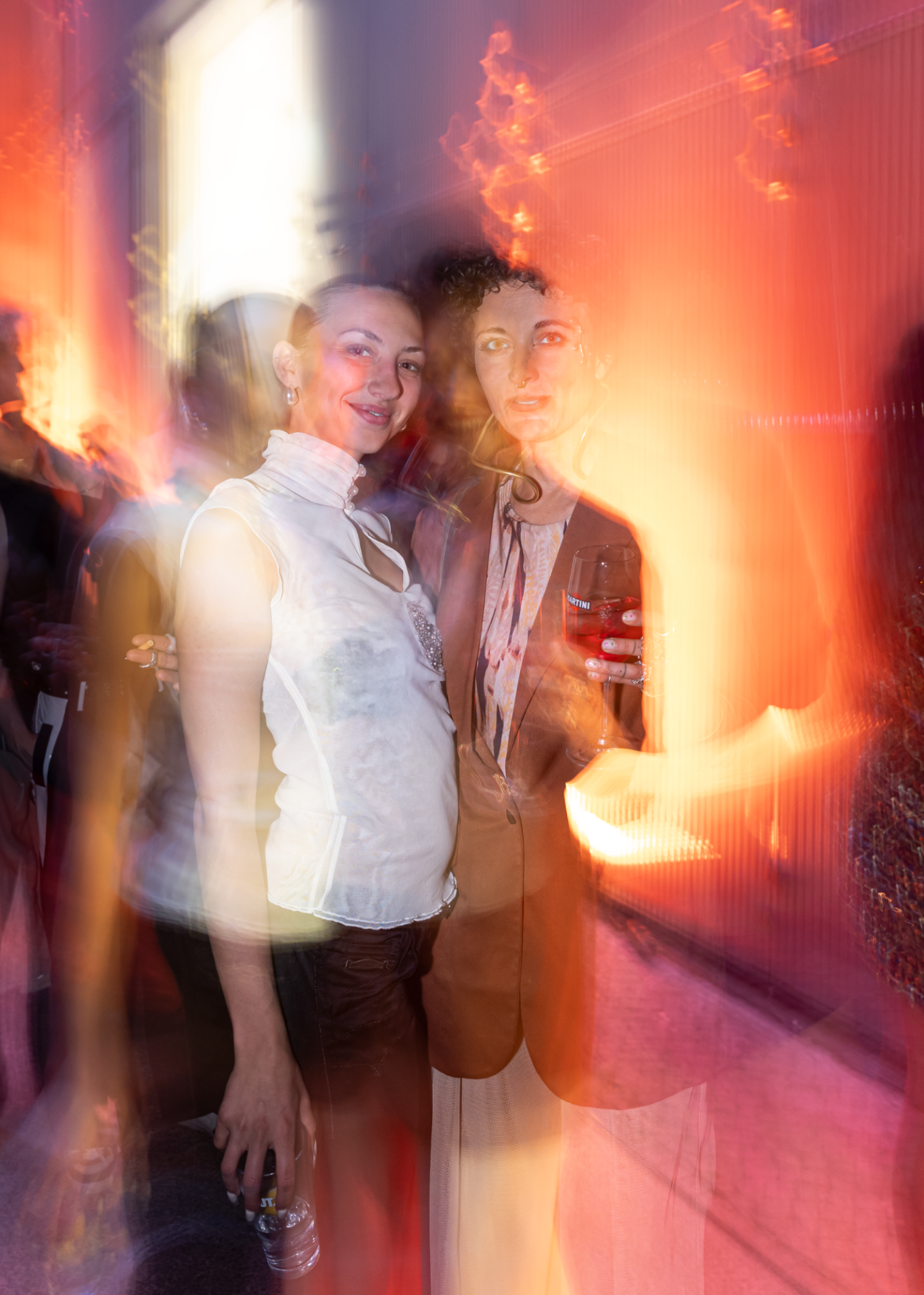 Zwei Personen in einer kreativen, verschwommenen Umgebung mit warmen Lichttönen.