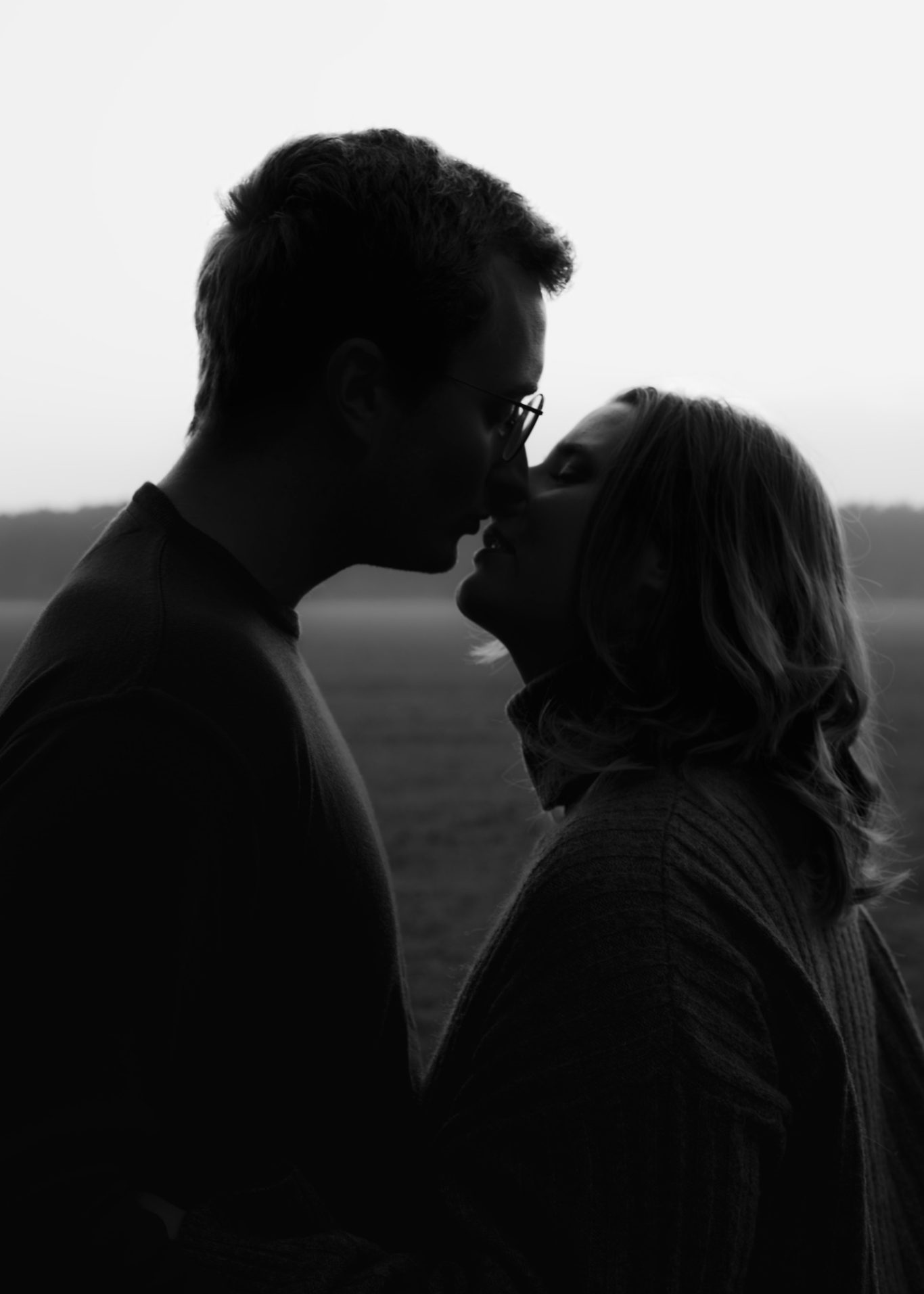 Liebespaar, das sich küsst, silhouettiert gegen einen sanften Hintergrund.