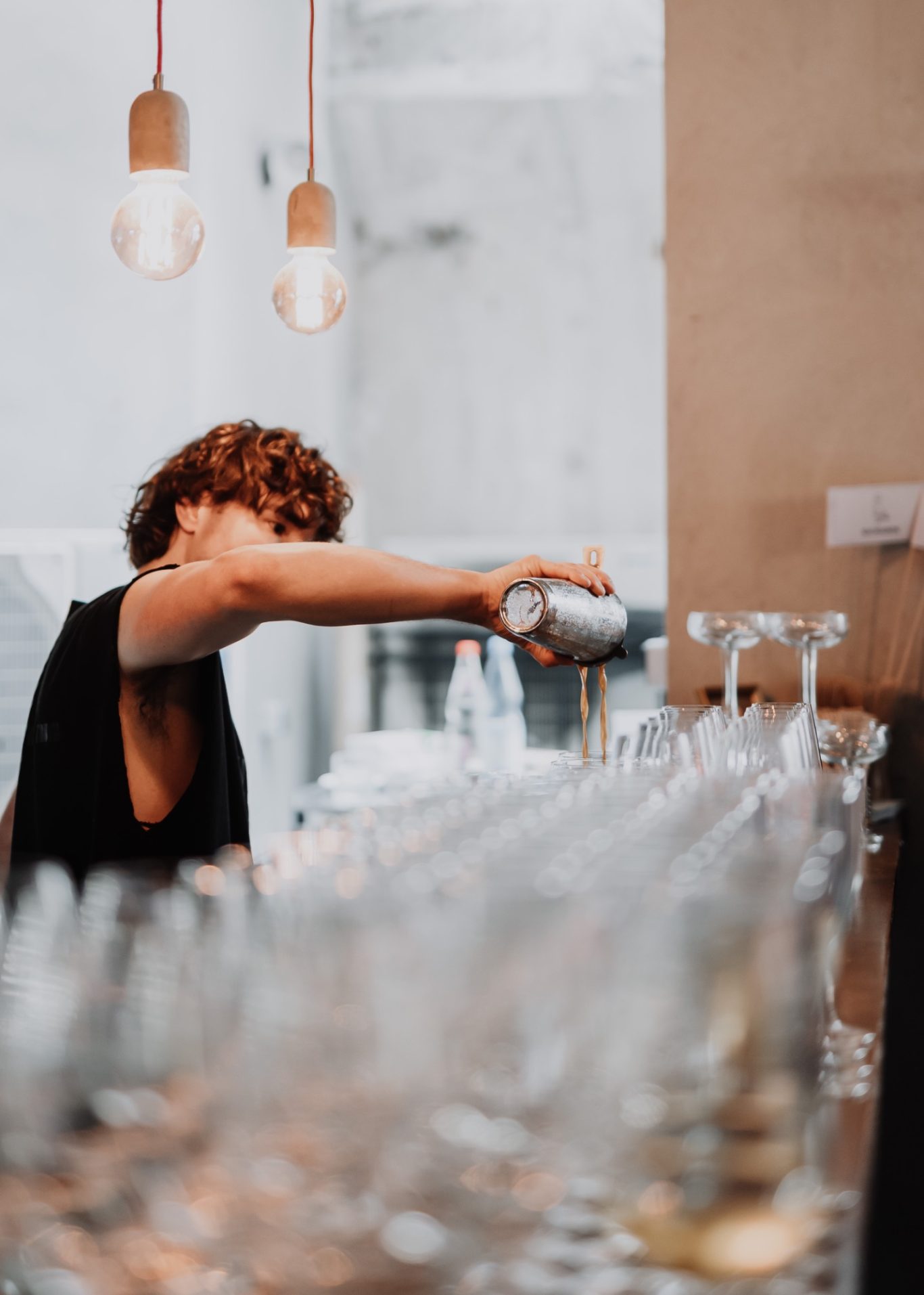 Barkeeper mixt Getränke hinter einer Bar mit vielen Gläsern.