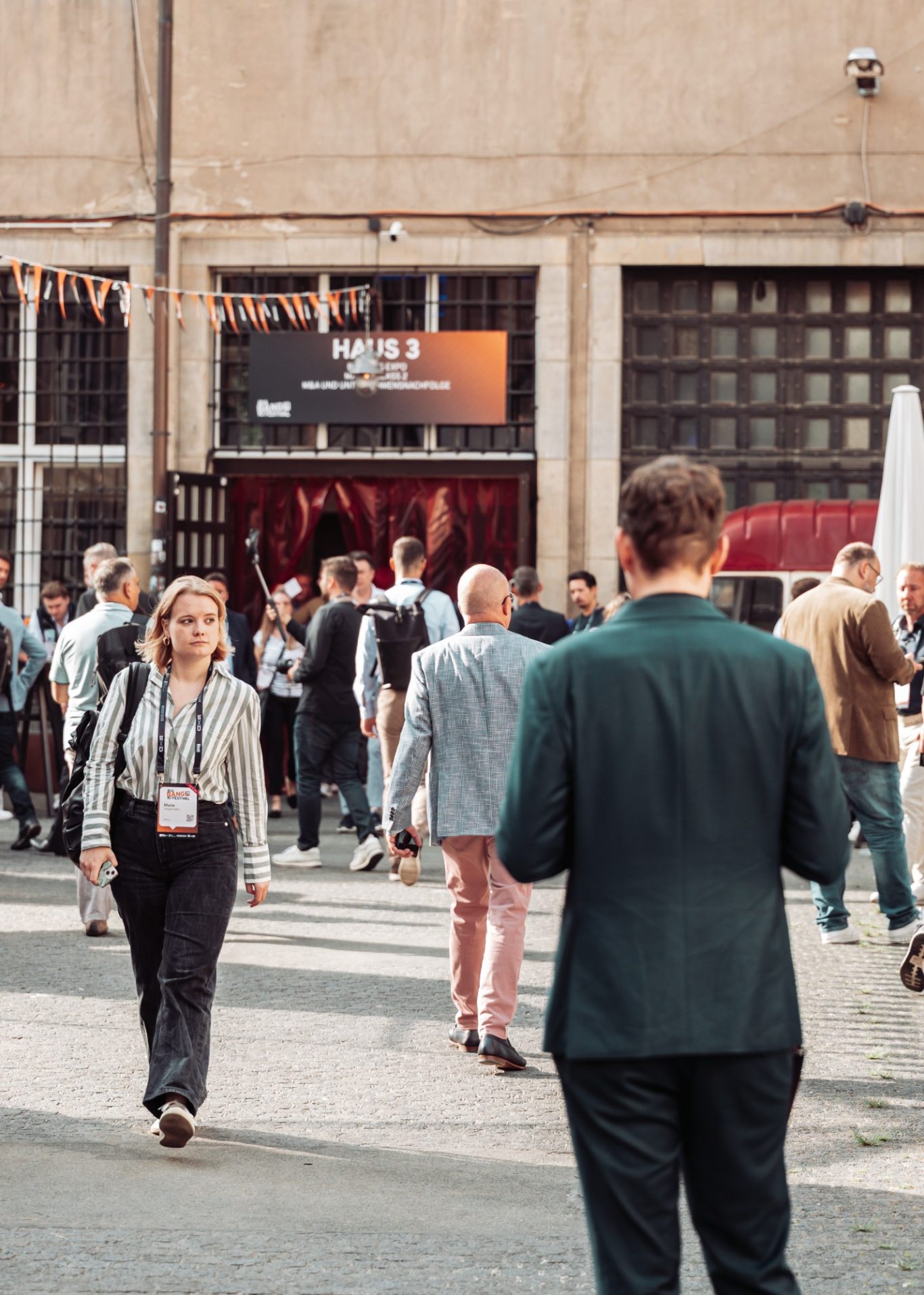 Menschenmenge vor einem Veranstaltungsort, einige in formeller Kleidung, andere leger gekleidet.