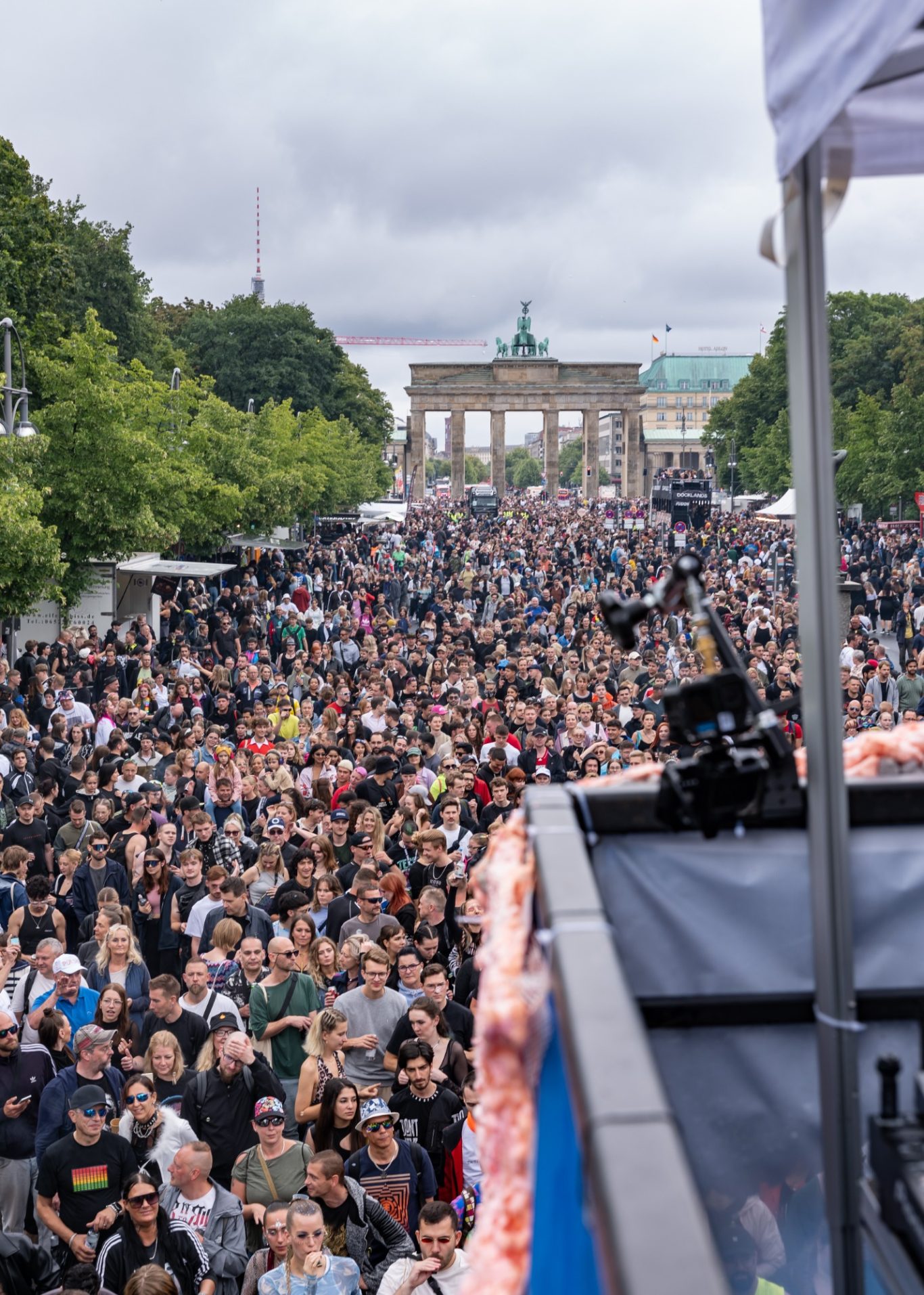Große Menschenmenge vor dem Brandenburger Tor bei einem Event, bewölkter Himmel.