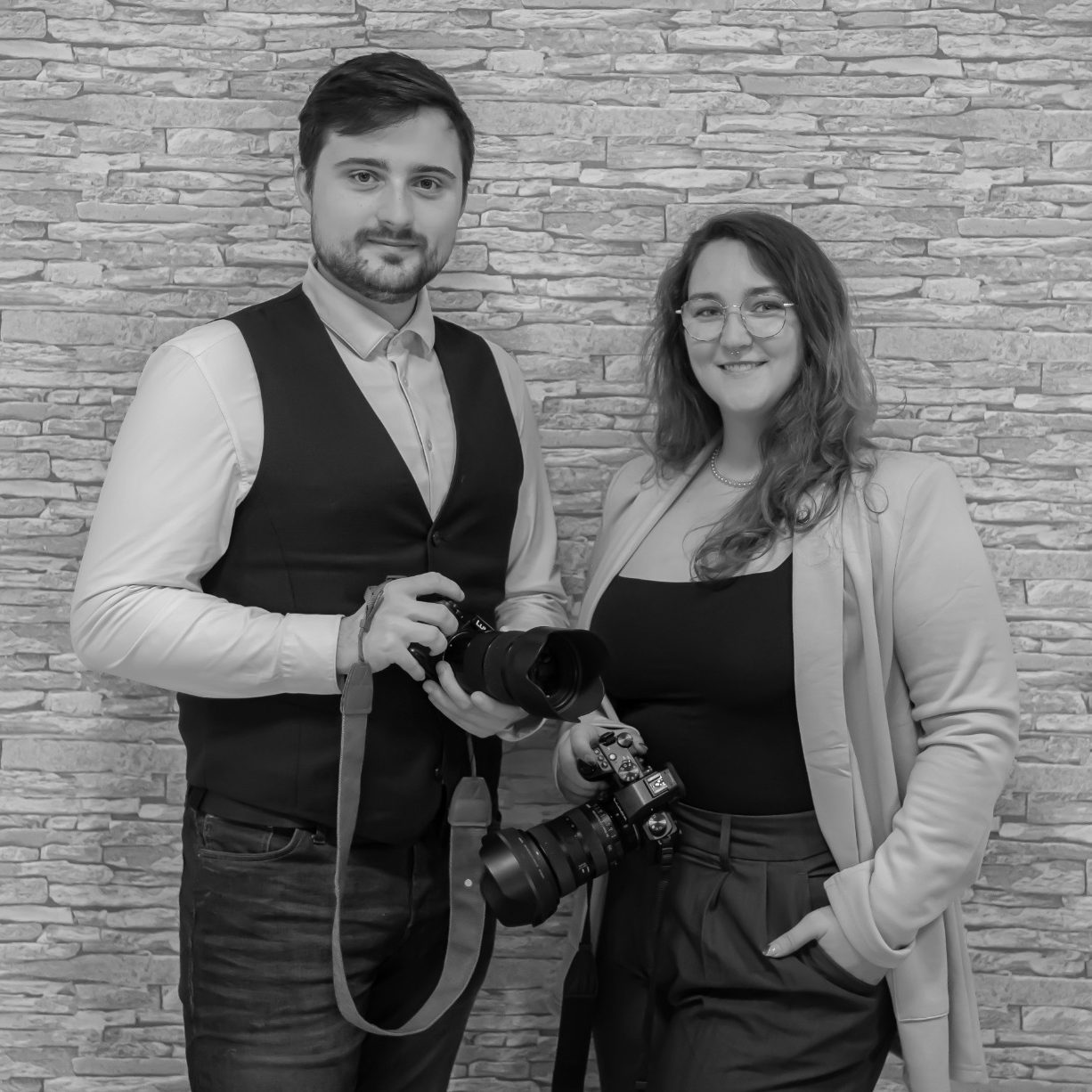 Ein Ehepaar küsst sich unter einem Holzbogen mit weißen Vorhängen. Beide halten den Brautstrauß neben sich.