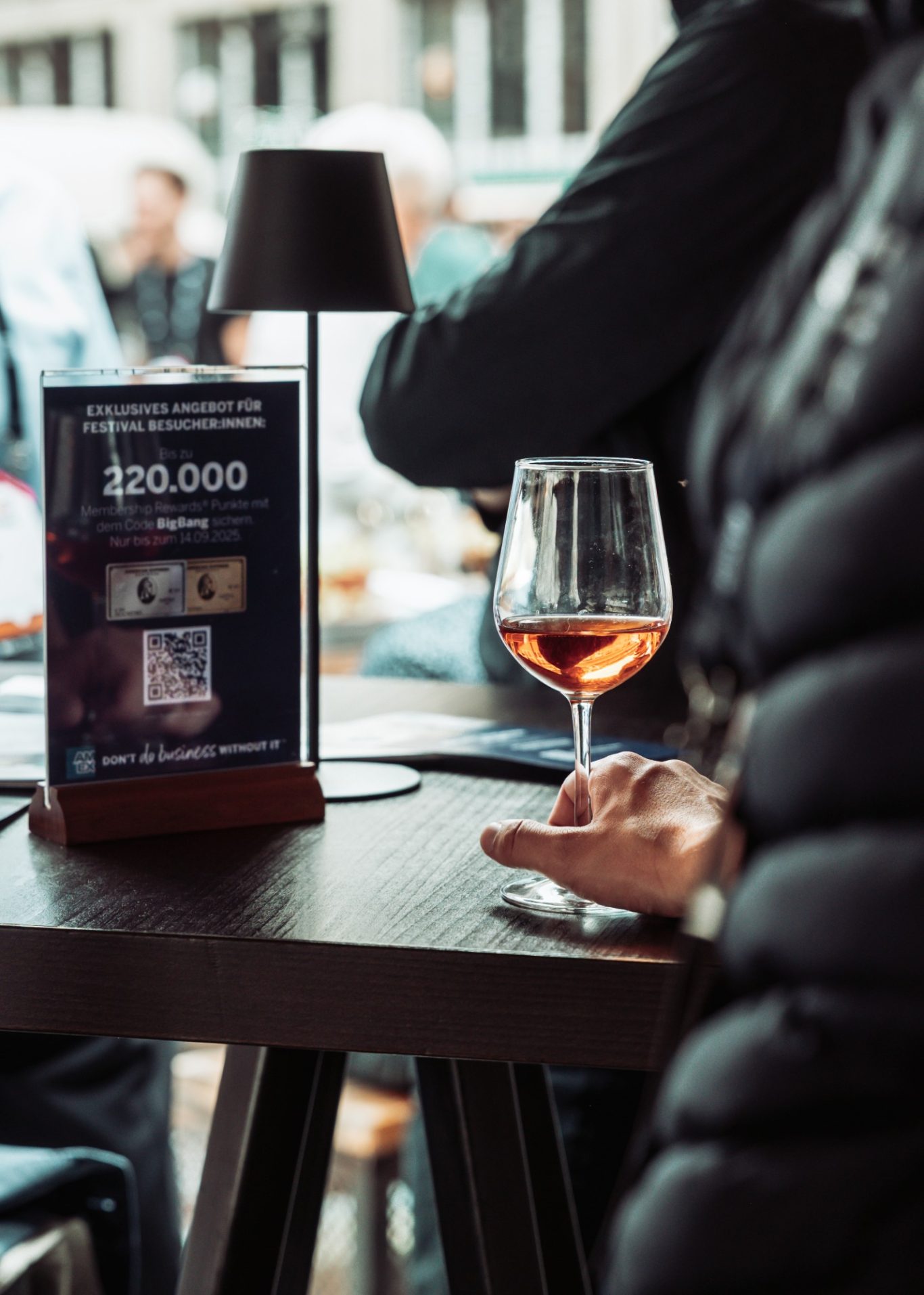 Ein Glas Roséwein auf einem Tisch mit einer Menükarte im Hintergrund.