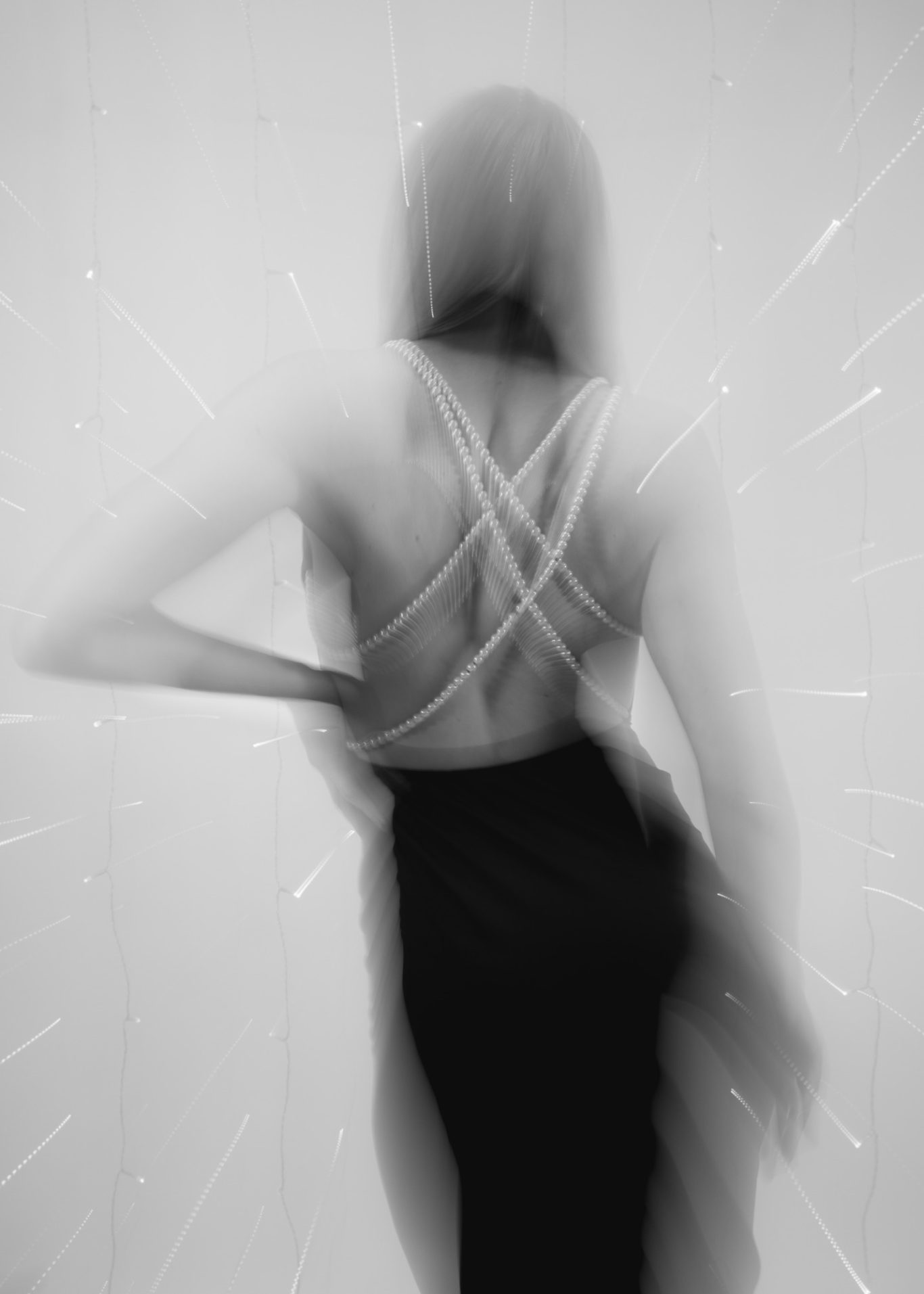 Schwarz-weißes Porträt einer Person von hinten in eleganter Kleidung mit unscharfem Hintergrund.