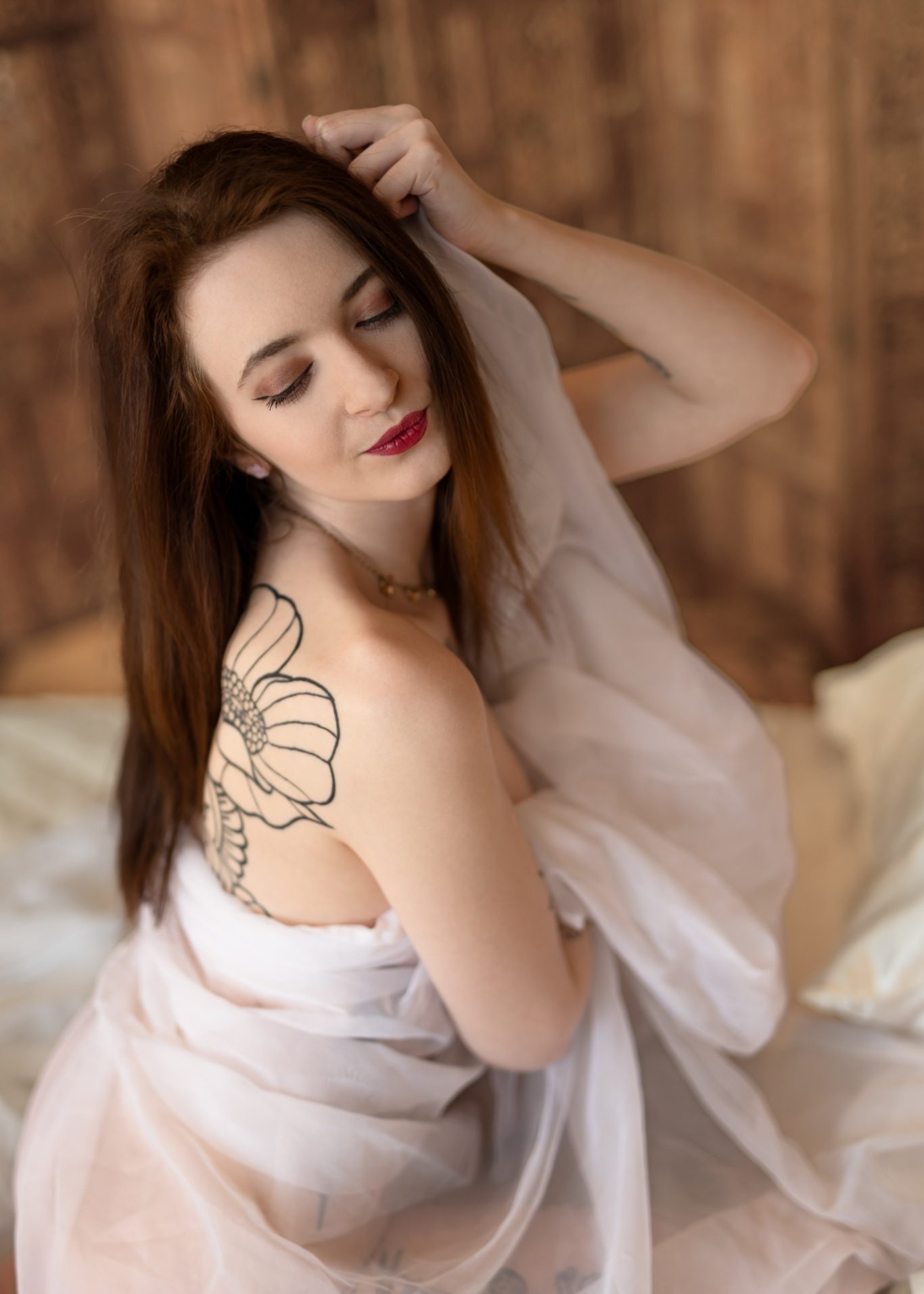 Frau mit langen Haaren und Blumen-Tattoo, umhüllt von transparentem Stoff.