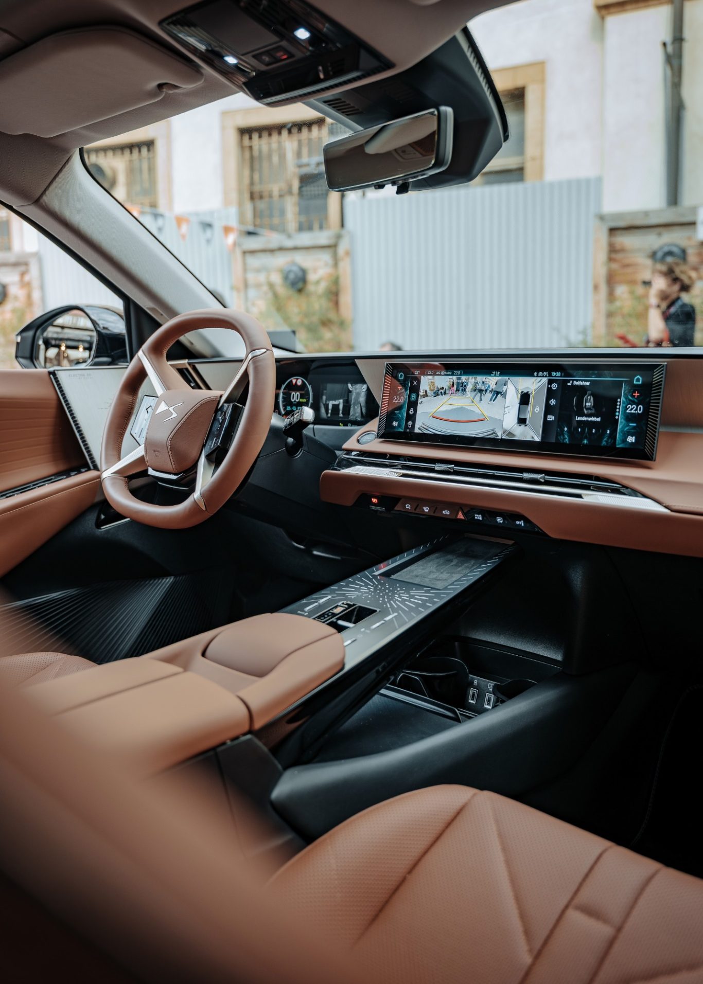 Innenansicht eines modernen Fahrzeugs mit braunem Lederinterieur und digitalem Display.