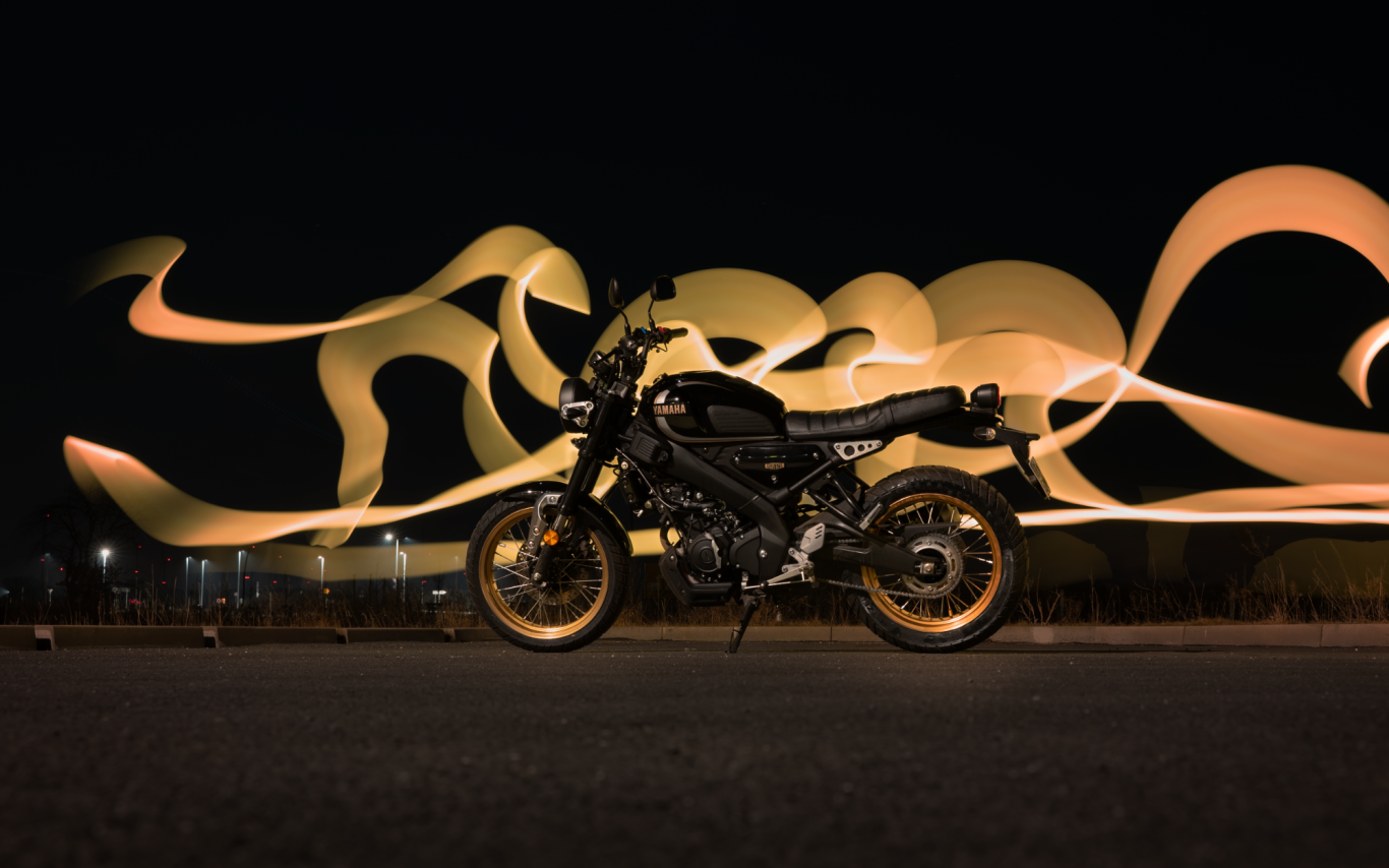 Ein Motorrad vor einem dunklen Hintergrund mit leuchtenden, geschwungenen Lichtlinien.